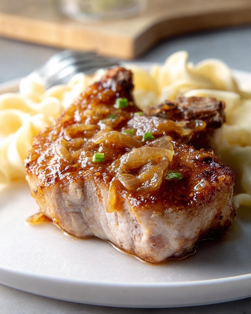 A juicy pork chop with a rich onion sauce and noodles, part of our 10-Ingredient Pork Chops Recipes.