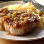A juicy 10-ingredient pork chop served with pasta and topped with a rich onion gravy and green onions.