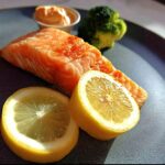 A perfectly cooked salmon fillet served with lemon slices, broccoli, and a side of sauce, showcasing 12-Ingredient Salmon Recipes.