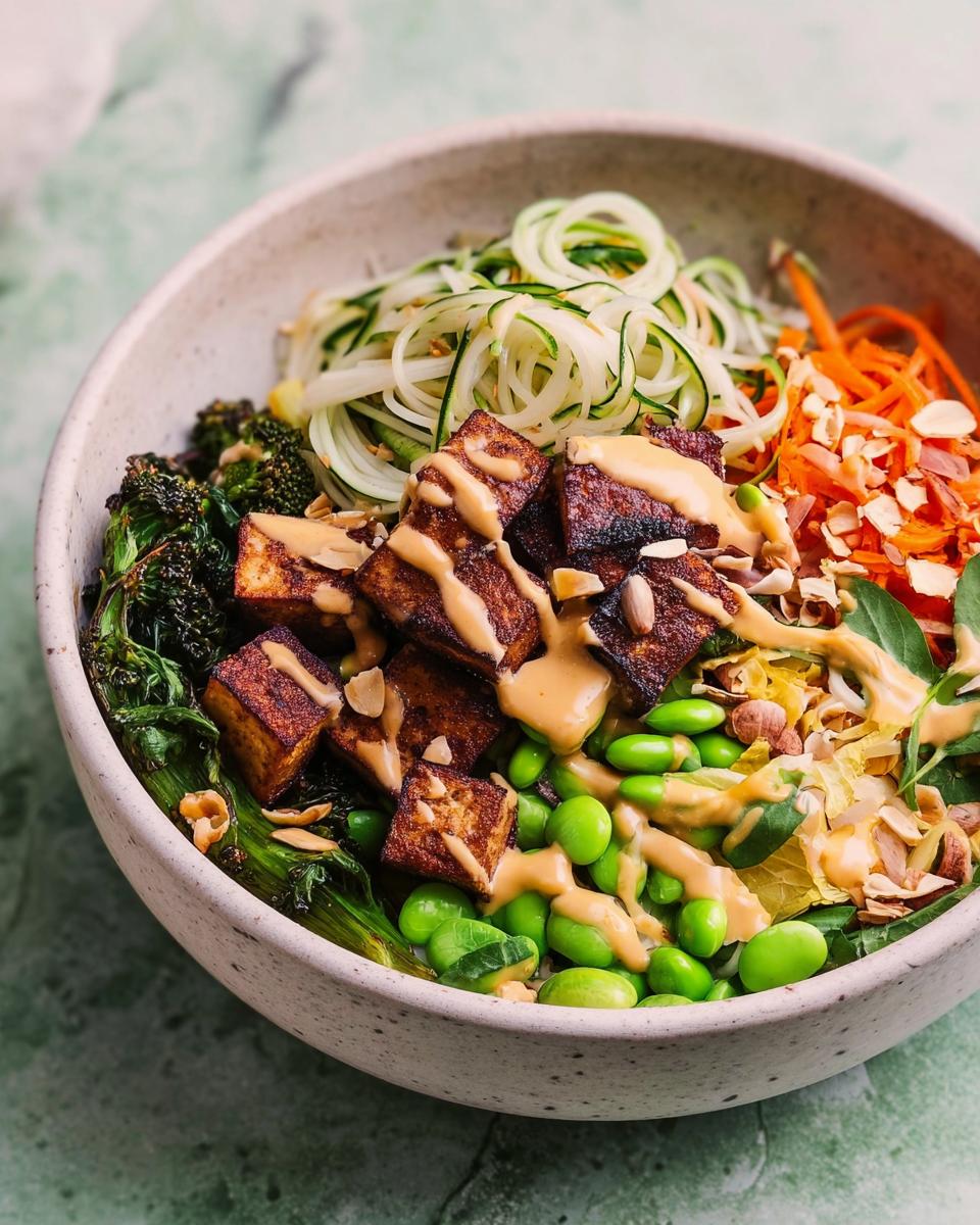 A vibrant and healthy 20-ingredient rice bowl featuring crispy tofu, edamame, zucchini noodles, and shredded carrots with a creamy dressing.