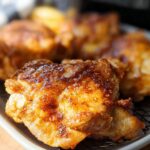 Close-up of golden brown, crispy air fryer chicken thighs seasoned with spices.
