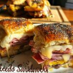 Close-up of two baked sandwich ideas recipes, filled with ham and melted cheese, topped with poppy seeds.