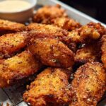 A close-up of perfectly seasoned and crispy chicken wings, ready to be served with dipping sauce.