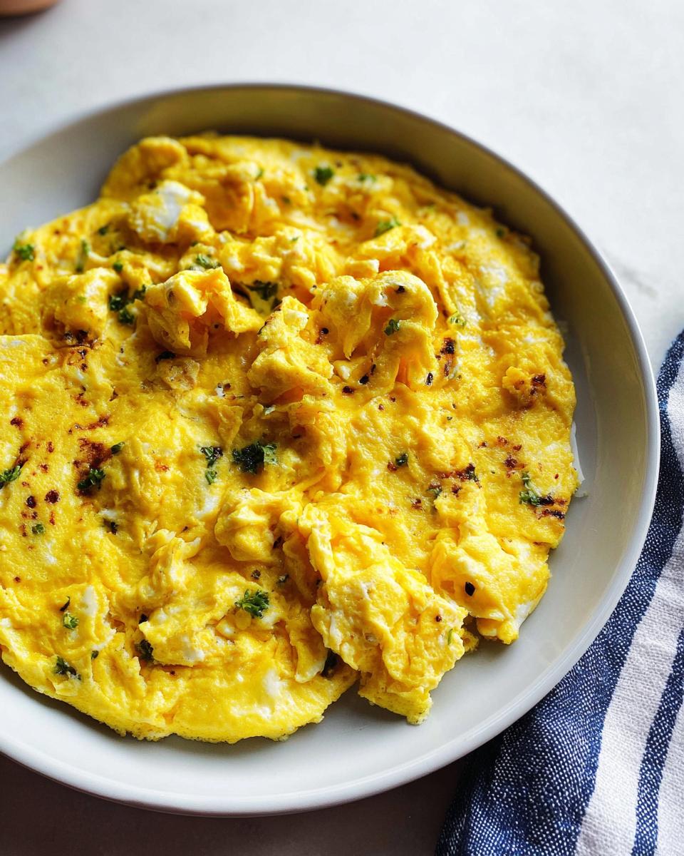 Close-up of fluffy scrambled eggs seasoned with herbs and spices, part of The Only Egg Recipes Recipe You’ll Need.