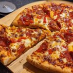 A delicious slice of pepperoni pizza with melted cheese and red pepper flakes, perfect for pizza night.