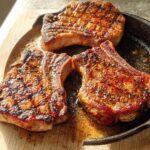 Three perfectly seared pork chops in a cast iron skillet, ready for a delicious pork chops recipe.