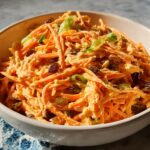 A bowl of shredded carrot salad with raisins and green onions, part of quick veggie sides recipes.