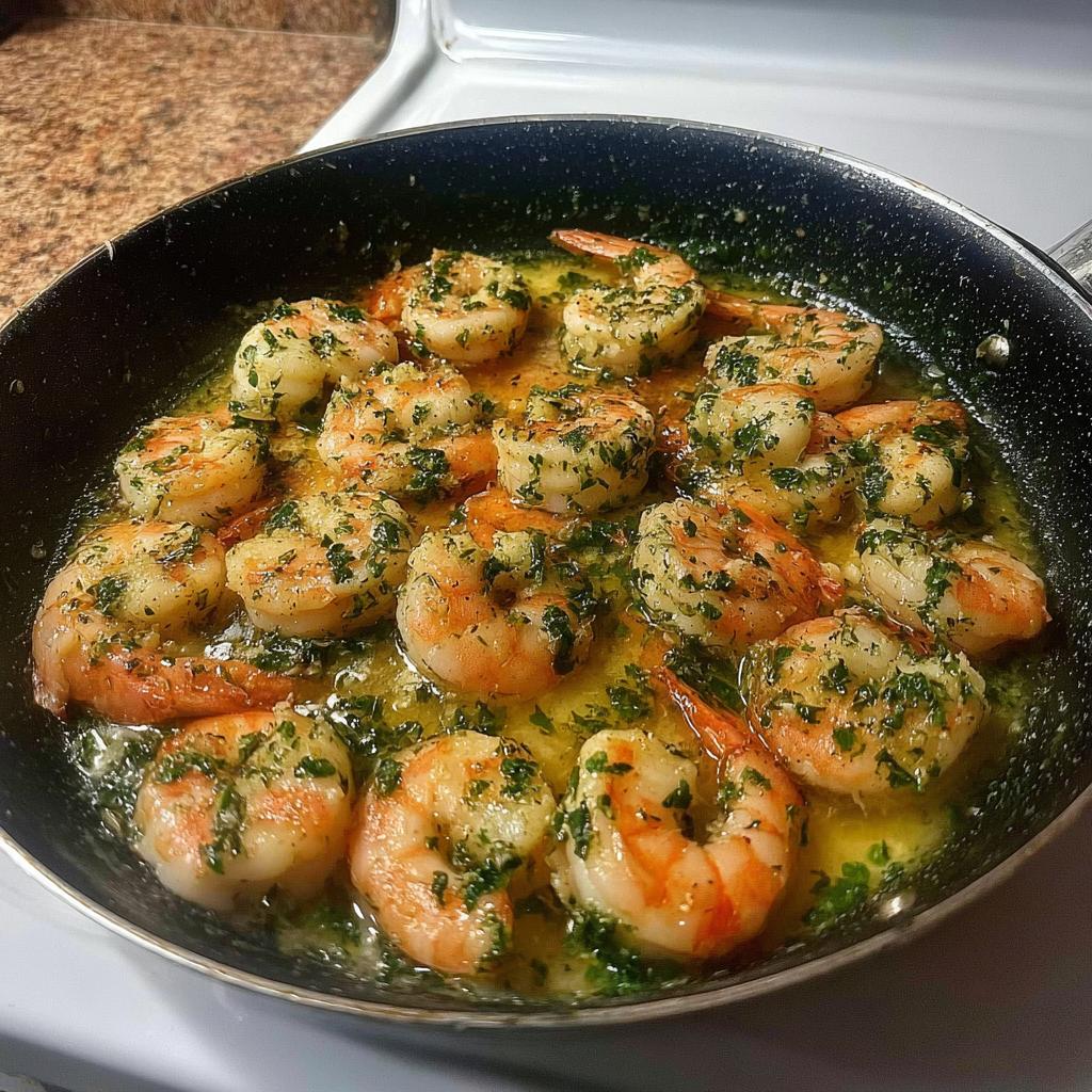 A close-up of restaurant-style shrimp recipes at home, cooked in garlic butter and herbs in a skillet.