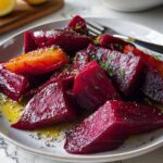 A plate of roasted beet wedges, drizzled with olive oil and sprinkled with herbs, as a delicious veggie side dish.