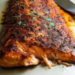 Close-up of a perfectly cooked salmon fillet with a crispy, spiced crust and flaky interior, a staple in salmon recipes.