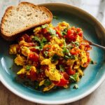 Scrambled egg recipes in 10 minutes with diced tomatoes and fresh cilantro, served with toast.