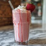 A refreshing homemade strawberry frappuccino, topped with whipped cream and a fresh strawberry, perfect for when you crave Starbucks drinks recipes.