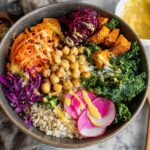 A vibrant and healthy vegetarian rice bowl recipe packed with brown rice, chickpeas, kale, shredded carrots, sweet potatoes, and red cabbage, drizzled with dressing.