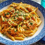 A close-up of creamy Cowboy Butter Chicken Pasta, garnished with fresh herbs and cheese.