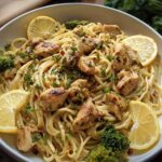 A bowl of Cowboy Butter Lemon Bowtie Chicken Pasta with Broccoli, garnished with lemon slices and fresh parsley.