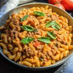 A bowl of Creamy High Protein Beef Pasta topped with fresh basil leaves.