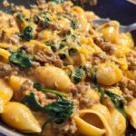 Close-up of Creamy High Protein Beef Pasta with spinach and melted cheese in a skillet.