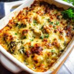 A close-up of a baked Creamy Low Carb Chicken Casserole in a white dish, topped with melted golden cheese and fresh parsley.