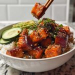 Close-up of a Crispy Salmon and Rice Bowl with glazed salmon cubes, avocado slices, cucumber, and sesame seeds.
