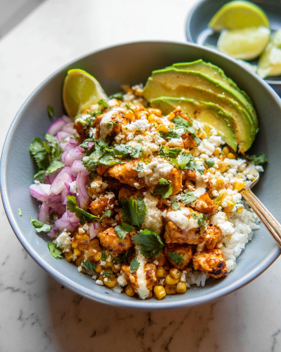 A close-up of an Easy Street Corn Chicken Bowl, featuring seasoned chicken, corn, rice, avocado, red onion, and crumbled cheese.