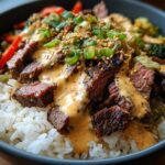 Close-up of Korean BBQ Steak Rice Bowls topped with spicy cream sauce, sesame seeds, and green onions.