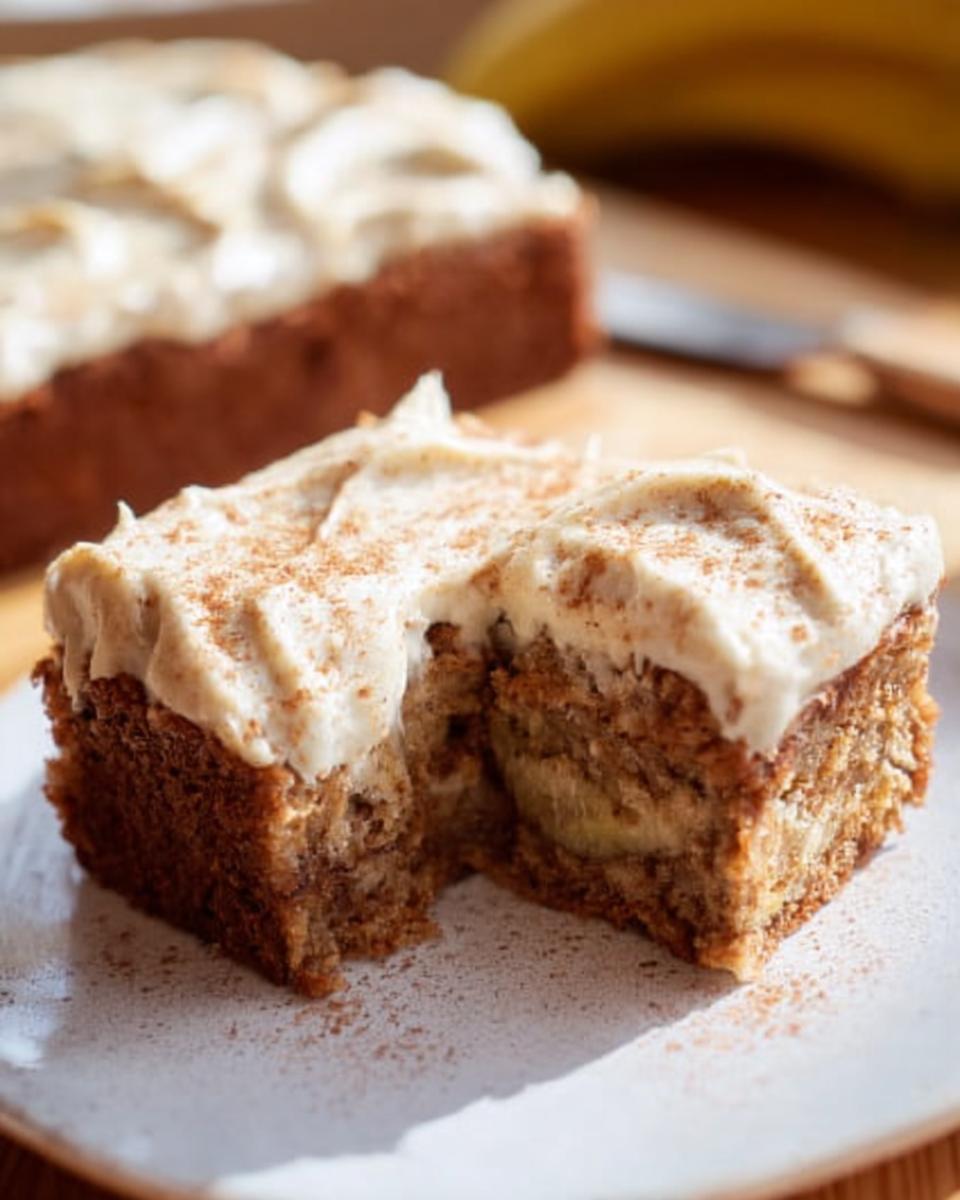 A slice of moist Banana Bread Brownies Made Easy topped with creamy frosting and a sprinkle of cinnamon.