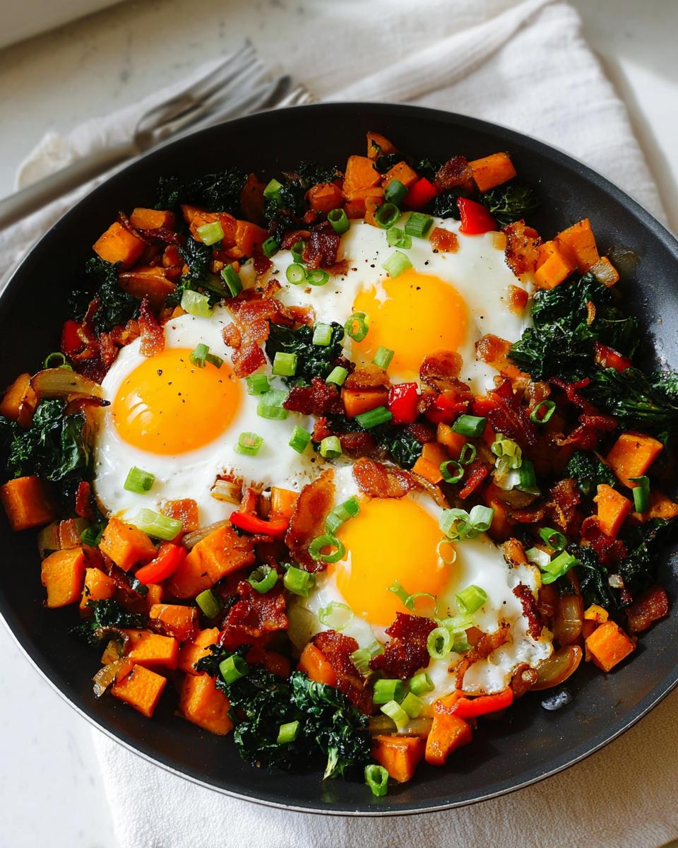 A hearty skillet of BREAKFAST SWEET POTATO hash with fried eggs, bacon, kale, and green onions.