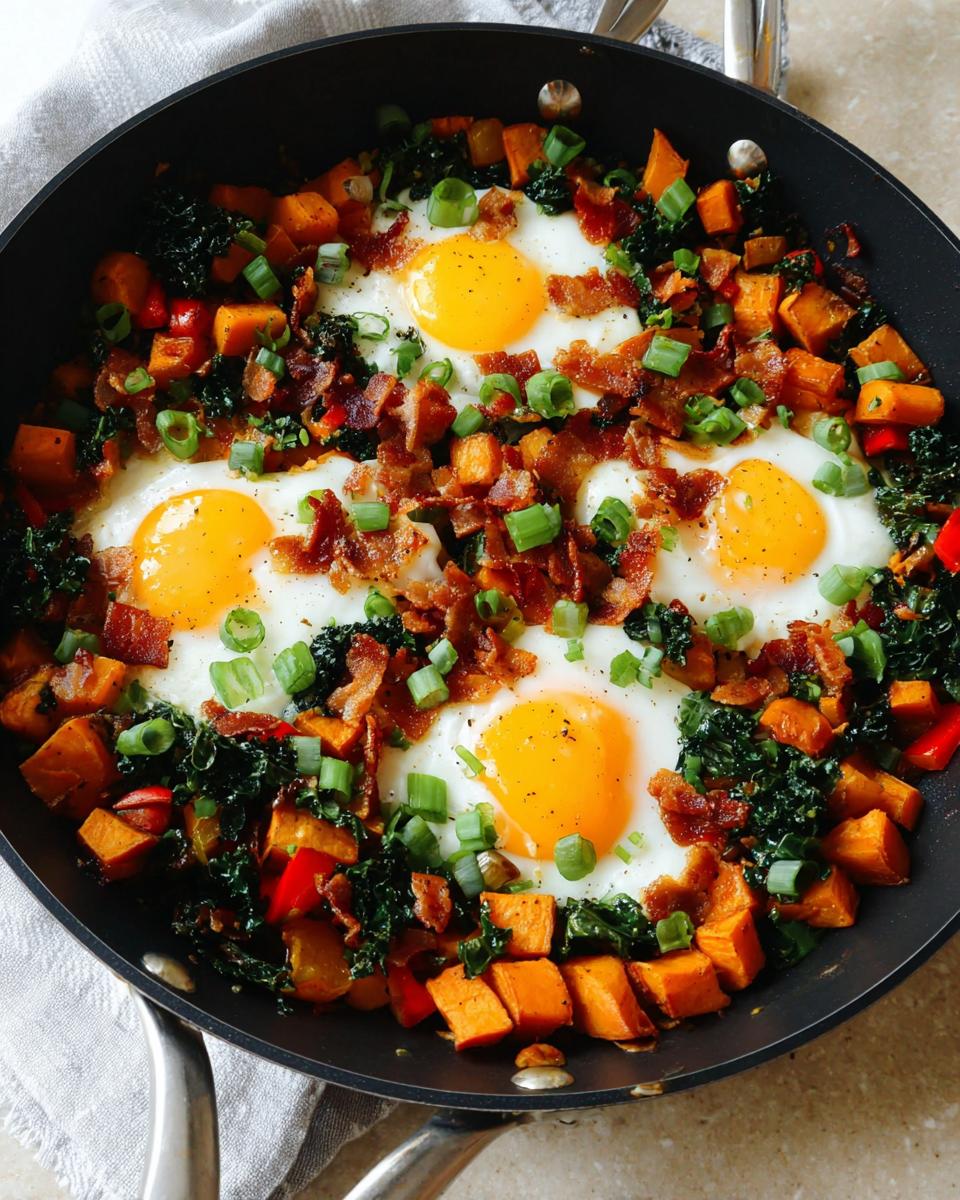 A skillet filled with a colorful BREAKFAST SWEET POTATO hash, topped with fried eggs, crispy bacon, and green onions.