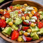 A vibrant bowl of Chickpea Feta Avocado Salad with cherry tomatoes, red onion, and herbs.