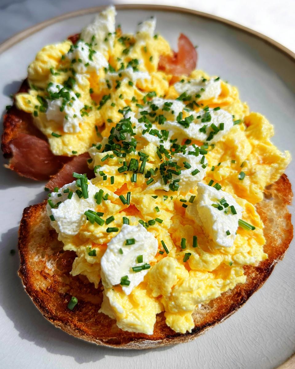 Close-up of Creamy Ricotta Egg Toast topped with fluffy scrambled eggs and fresh chives.