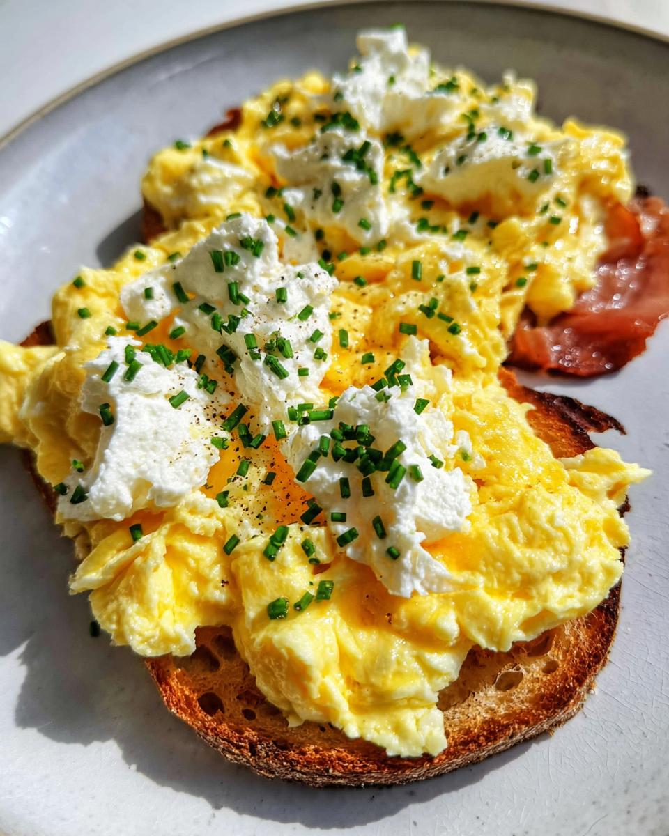 Close-up of Creamy Ricotta Egg Toast topped with fluffy scrambled eggs, dollops of ricotta, and fresh chives.