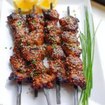 Close-up of Easy Japanese Chicken Yakitori Skewers glazed and sprinkled with sesame seeds and chili flakes.