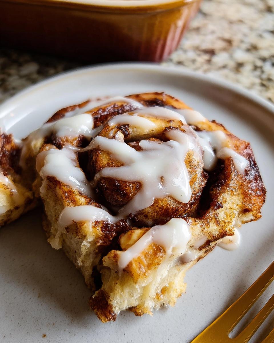 A close-up of a slice of High-Protein Cinnamon Roll Bread, drizzled with white icing.