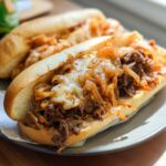 A close-up of a Spicy Kimchi Bulgogi Cheesesteak sandwich overflowing with bulgogi beef, kimchi, and melted cheese on a toasted bun.