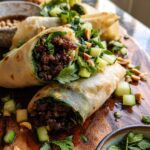 Close-up of Thai Basil Beef Rolls filled with savory ground beef and fresh herbs, topped with cucumber and peanuts.