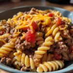 A bowl of cheesy taco pasta with ground beef and diced tomatoes, a perfect ground beef recipe for weeknights.