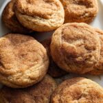 A close-up of several Chewy Churro Cookies, generously coated in cinnamon sugar, piled on a white platter.