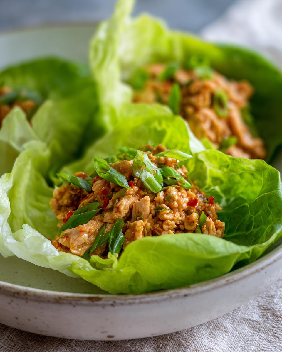 Close-up of fresh chicken lettuce wraps, a healthy lunch idea, topped with chopped green onions.