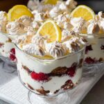 Close-up of individual servings of Chocolade Lasagne dessert, layered with cream, raspberries, and meringue, topped with lemon slices.
