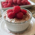 A close-up of Cottage Cheese Raspberry Mousse topped with fresh raspberries and dusted with cocoa powder.