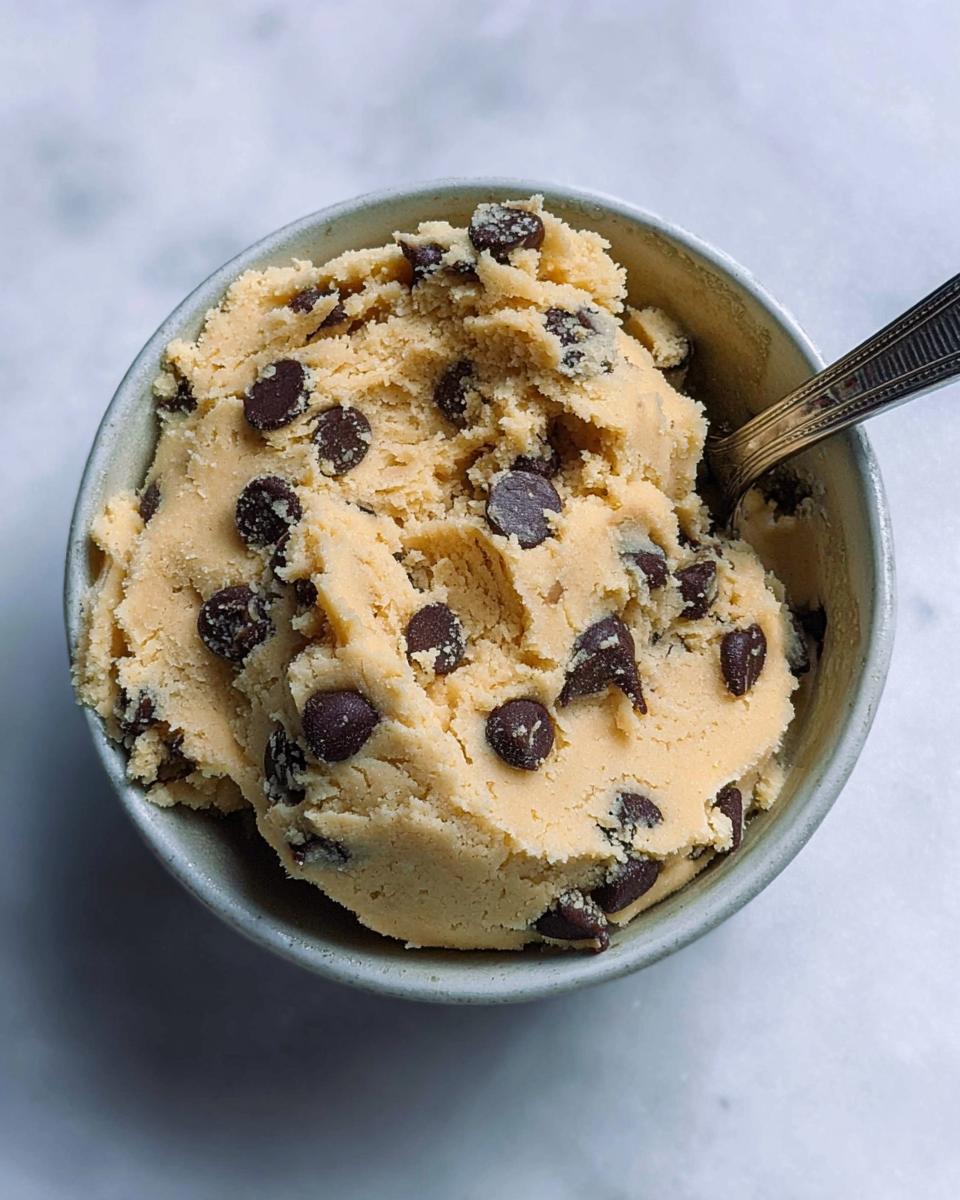 A bowl of delicious protein cookie dough loaded with chocolate chips, ready to be eaten.