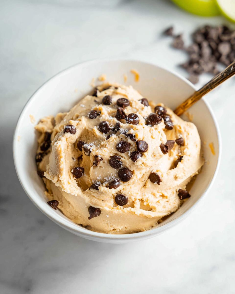 A bowl of creamy Greek yogurt cookie dough topped with mini chocolate chips and a sprinkle of sea salt.