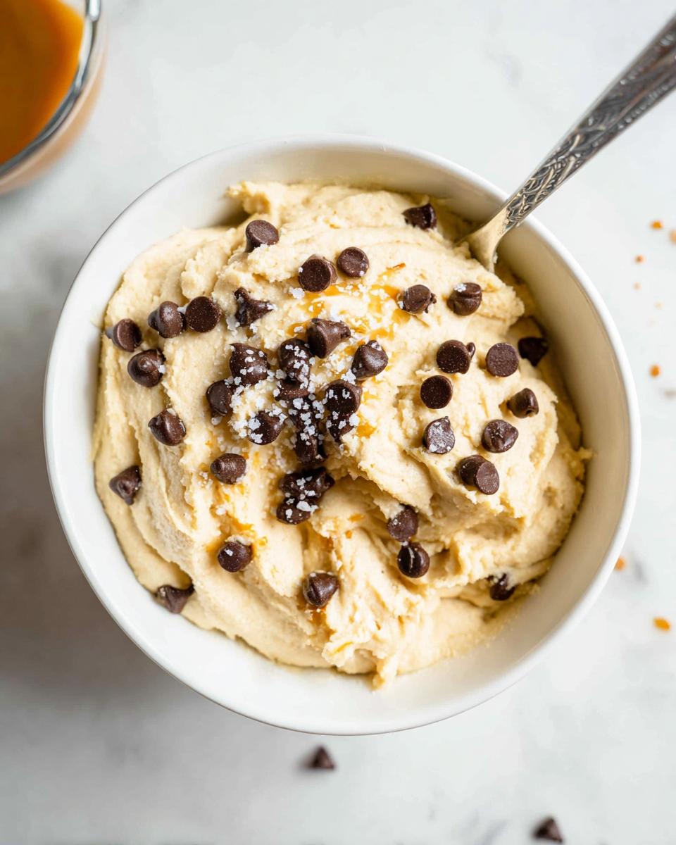 A bowl of creamy Greek yogurt cookie dough topped with chocolate chips and sea salt.