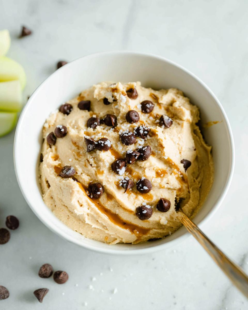 A bowl of delicious Greek Yogurt Cookie Dough topped with chocolate chips and sea salt, ready to be eaten with a spoon.