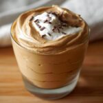 A serving of High-Protein Cottage Cheese Peanut Butter Mousse topped with whipped cream and chocolate shavings in a glass.