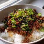 Close-up of Korean Beef Rice Bowls, featuring seasoned ground beef over white rice, topped with green onions and sesame seeds.