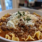 A close-up of a bowl of lasagna soup recipes with melty cheese on top, featuring pasta and rich meat sauce.