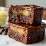 Two stacked Mini Pineapple Upside-Down Cheesecakes topped with chocolate glaze, showing pineapple chunks inside.