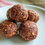 A close-up of four No-Bake Chocolate Peanut Butter Protein Balls stacked on a light gray plate.