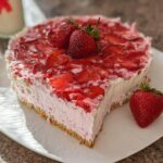 A slice of no-bake strawberry cloud cake on a white plate, topped with fresh strawberries.